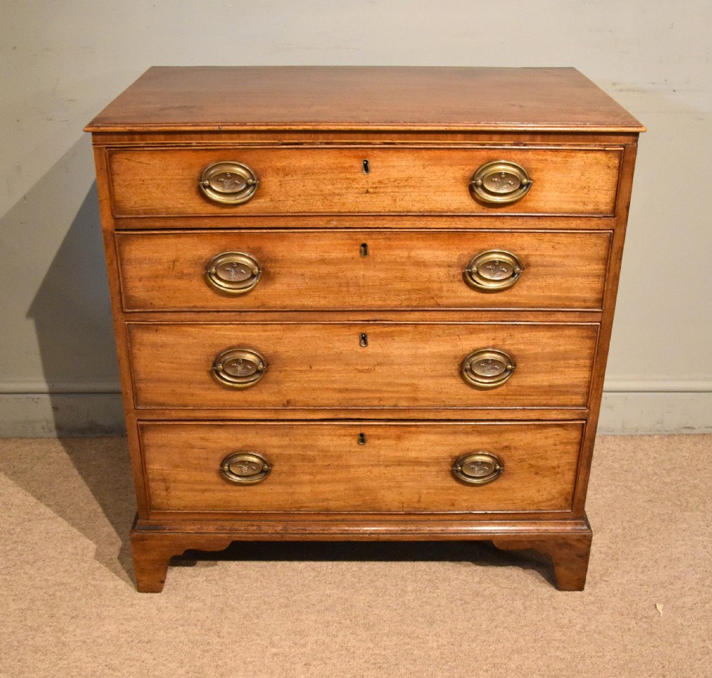 A George III mahogany chest of drawers featuring four graduated drawers with oval brass plate handles and shaped bracket feet.