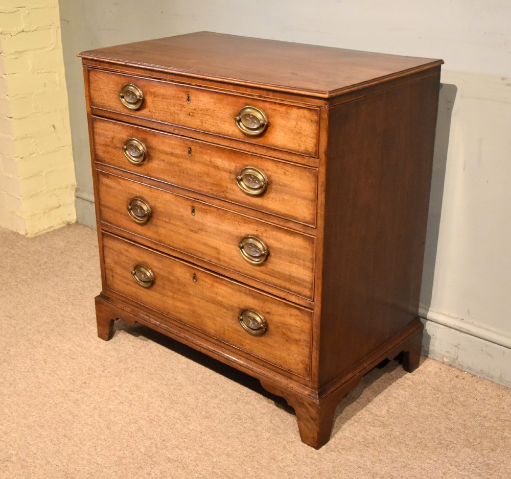 A George III mahogany chest of drawers featuring four graduated drawers with oval brass plate handles and shaped bracket feet. View III