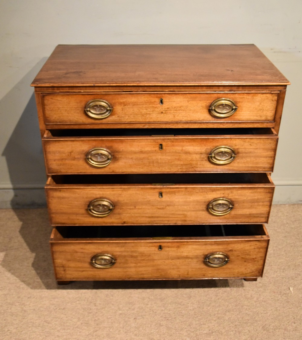 A George III mahogany chest of drawers featuring four graduated drawers with oval brass plate handles and shaped bracket feet. View V