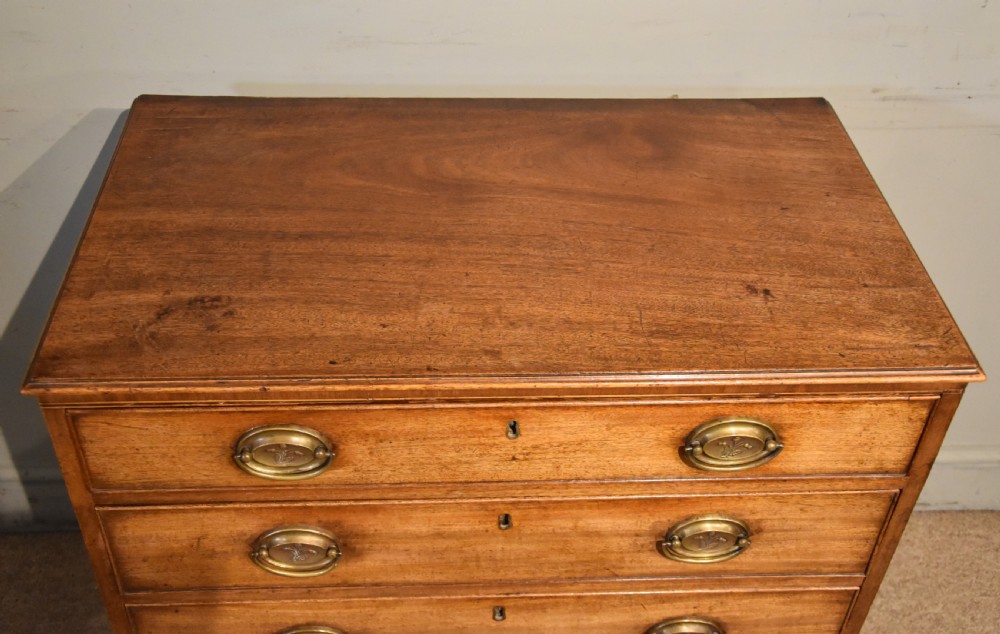 A George III mahogany chest of drawers featuring four graduated drawers with oval brass plate handles and shaped bracket feet. View VI