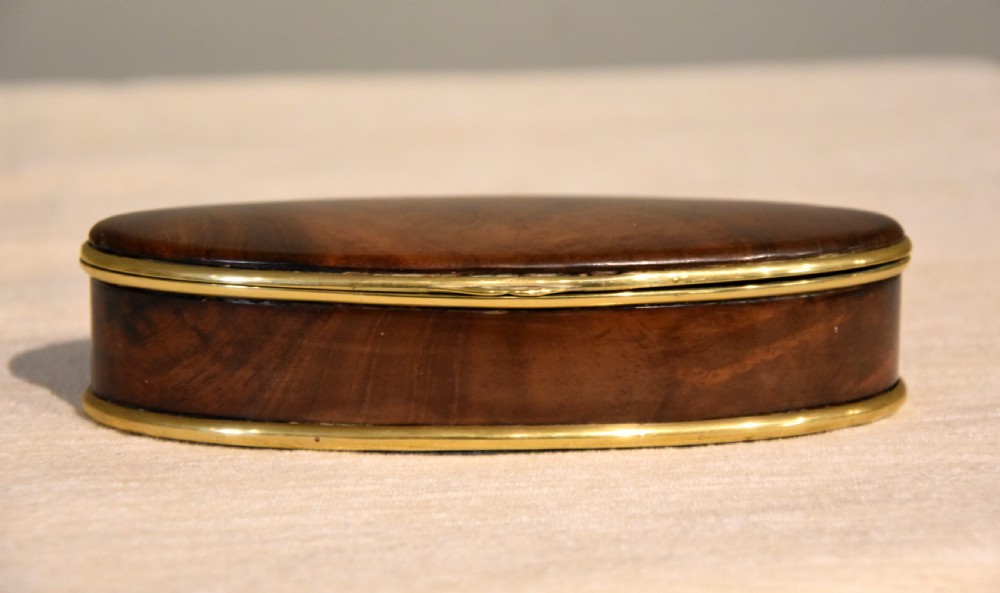 An eighteenth-century oval walnut table snuff box with figured grain and polished brass rim bindings. View IV