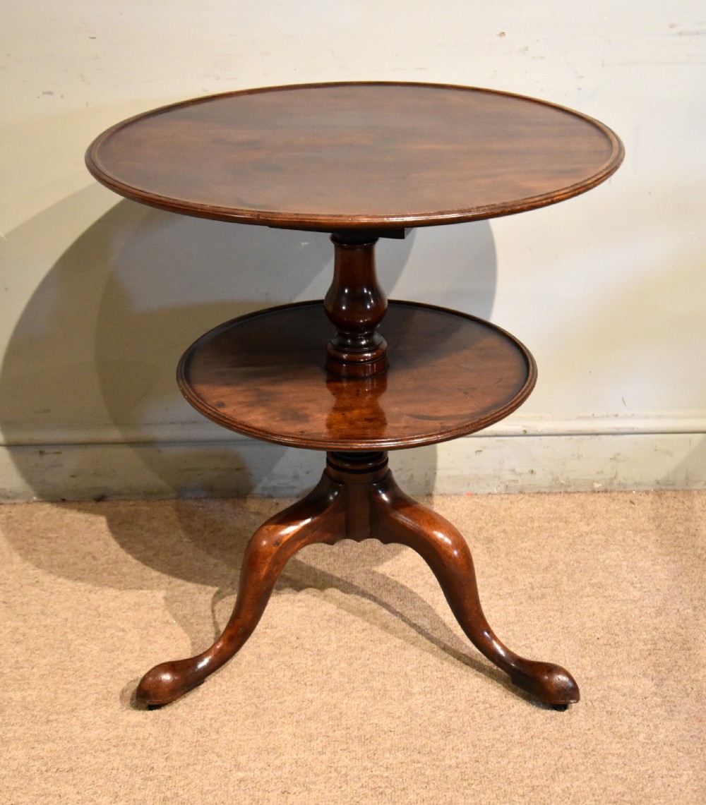 A George III mahogany two-tier tripod table featuring two circular trays supported by a central turned baluster stem and three cabriole legs ending in pad feet. View II