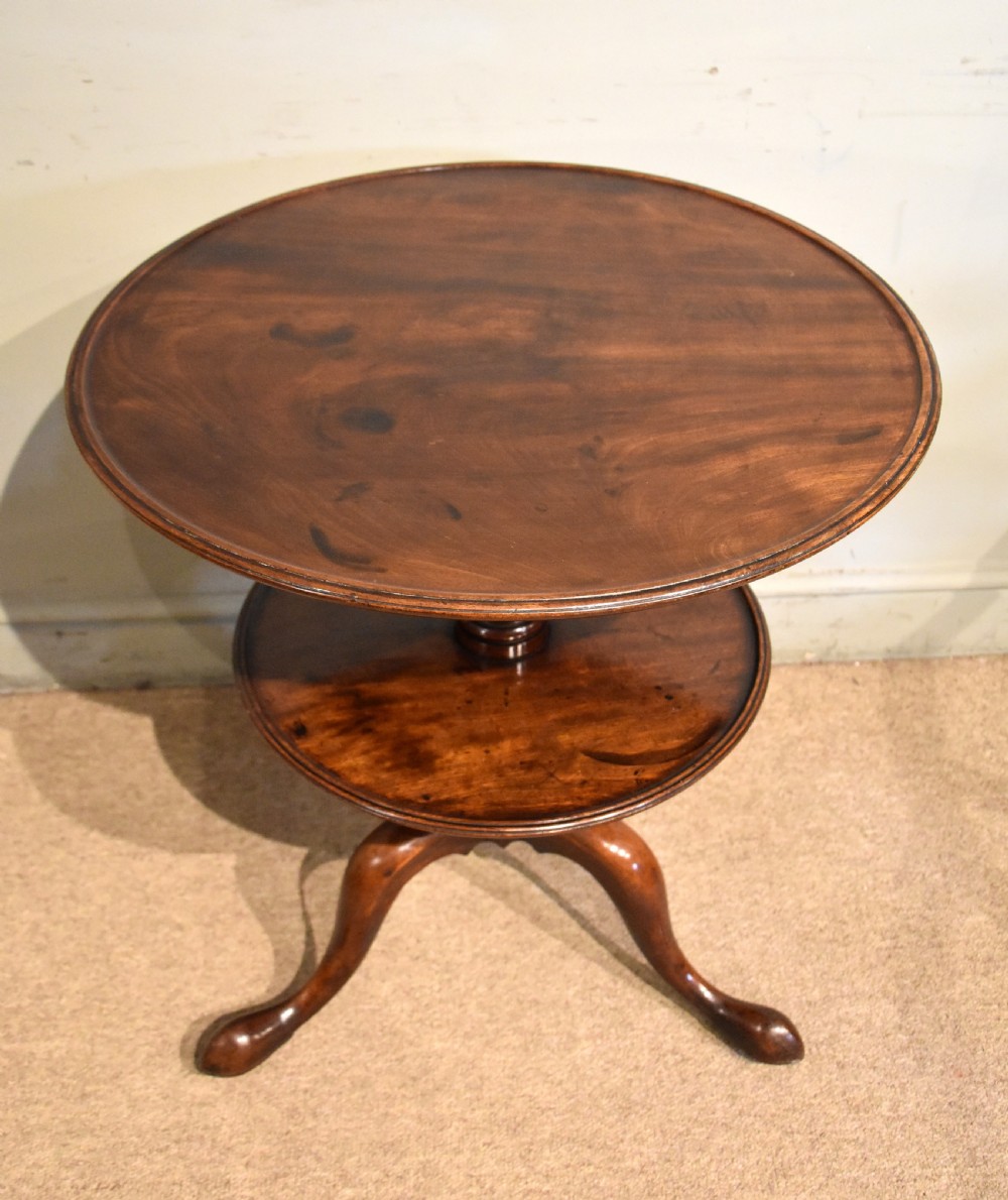 A George III mahogany two-tier tripod table featuring two circular trays supported by a central turned baluster stem and three cabriole legs ending in pad feet. View IV