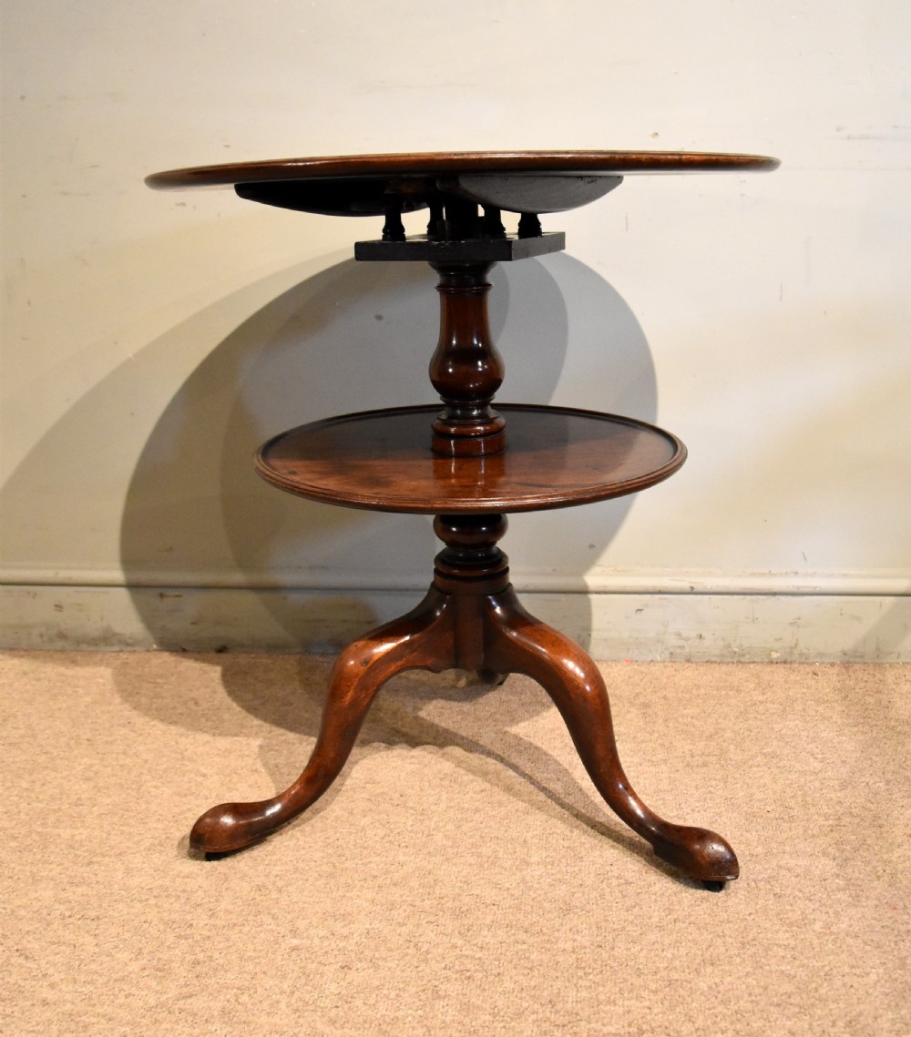 A George III mahogany two-tier tripod table featuring two circular trays supported by a central turned baluster stem and three cabriole legs ending in pad feet. View VI