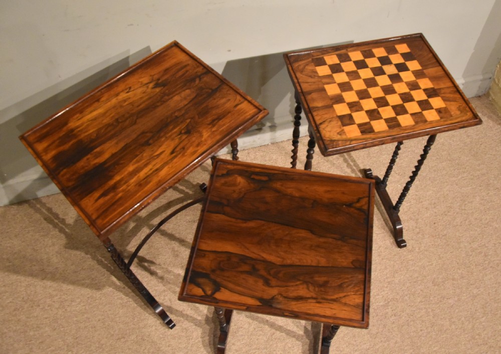 A set of three nested Regency rosewood occasional tables featuring barley twist legs, curved stretchers, and an inlaid chessboard top on the middle table. View V