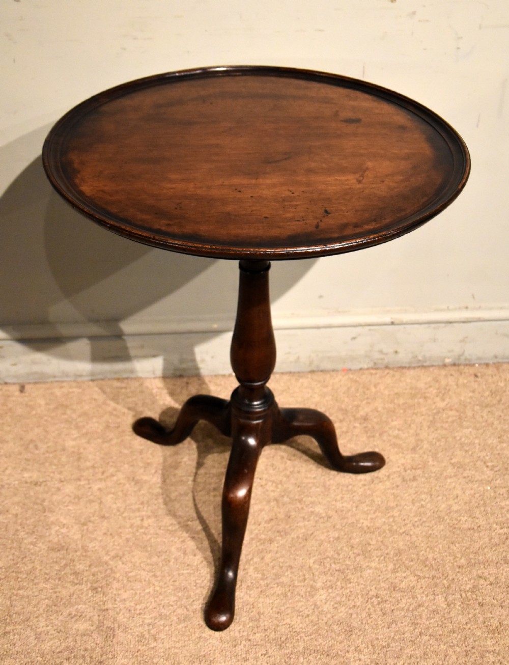 A George III mahogany wine table featuring a circular tilt top surface mounted on a turned pedestal stem and tripod legs. View III