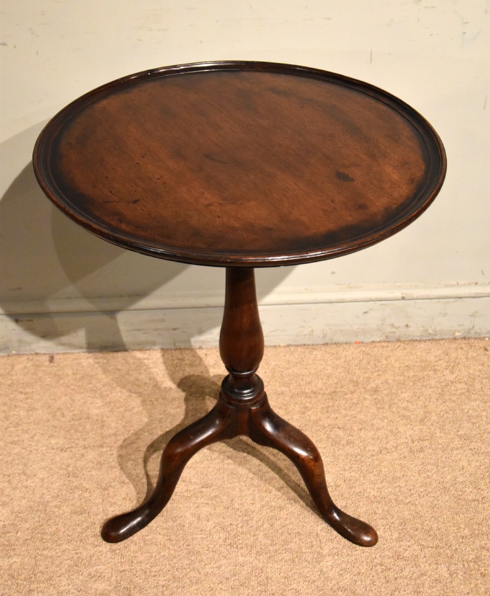 A George III mahogany wine table featuring a circular tilt top surface mounted on a turned pedestal stem and tripod legs. View V