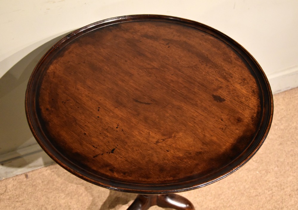 A George III mahogany wine table featuring a circular tilt top surface mounted on a turned pedestal stem and tripod legs. View VI