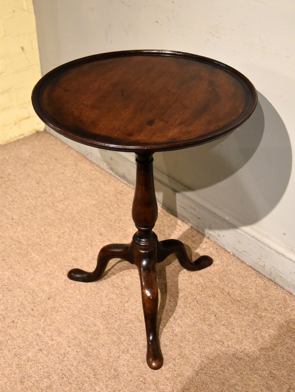 A George III mahogany wine table featuring a circular tilt top surface mounted on a turned pedestal stem and tripod legs. View VII