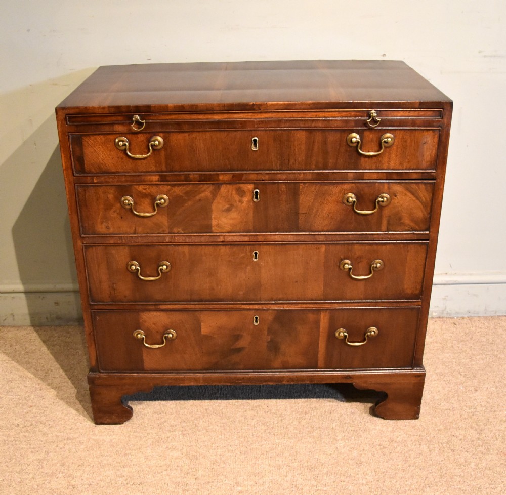 A George III walnut veneered chest of drawers with four graduated drawers, brass handles, and bracket feet.