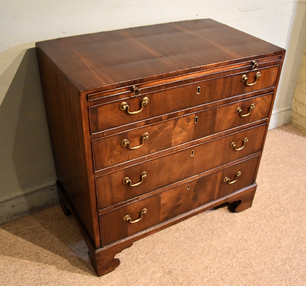 A George III walnut veneered chest of drawers with four graduated drawers, brass handles, and bracket feet. View II