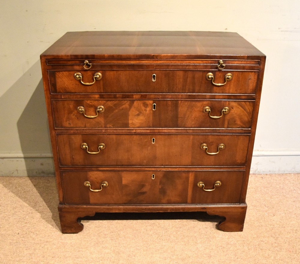 A George III walnut veneered chest of drawers with four graduated drawers, brass handles, and bracket feet. View III