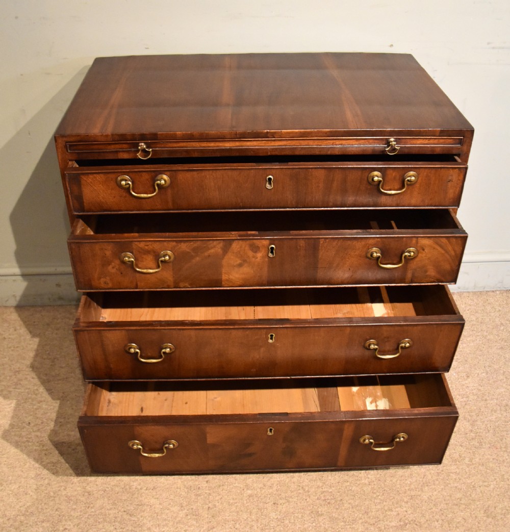 A George III walnut veneered chest of drawers with four graduated drawers, brass handles, and bracket feet. View IV