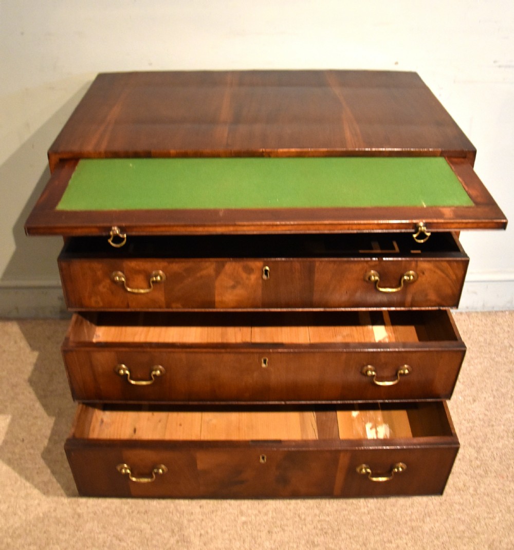 A George III walnut veneered chest of drawers with four graduated drawers, brass handles, and bracket feet. View V