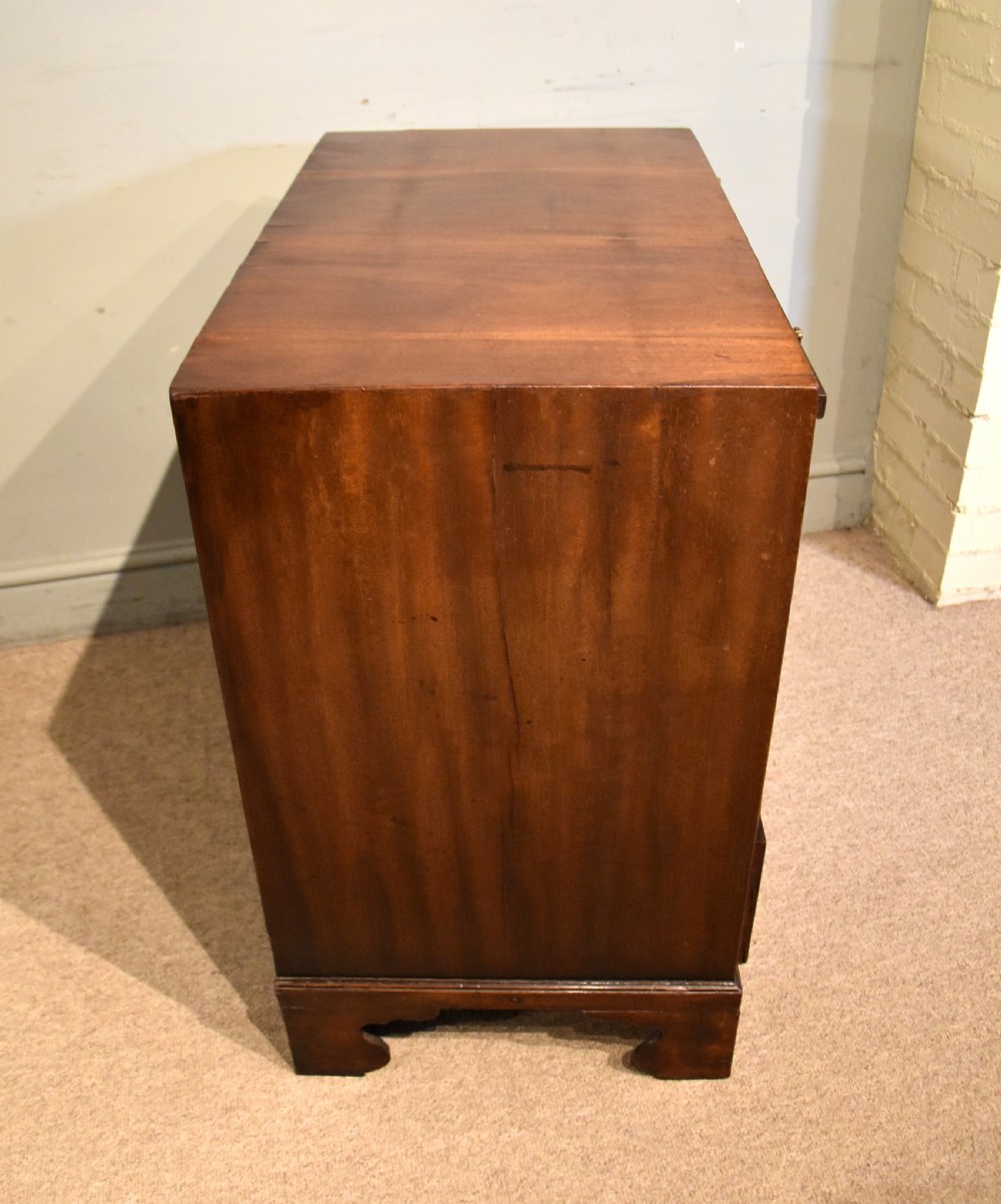 A George III walnut veneered chest of drawers with four graduated drawers, brass handles, and bracket feet. View VII