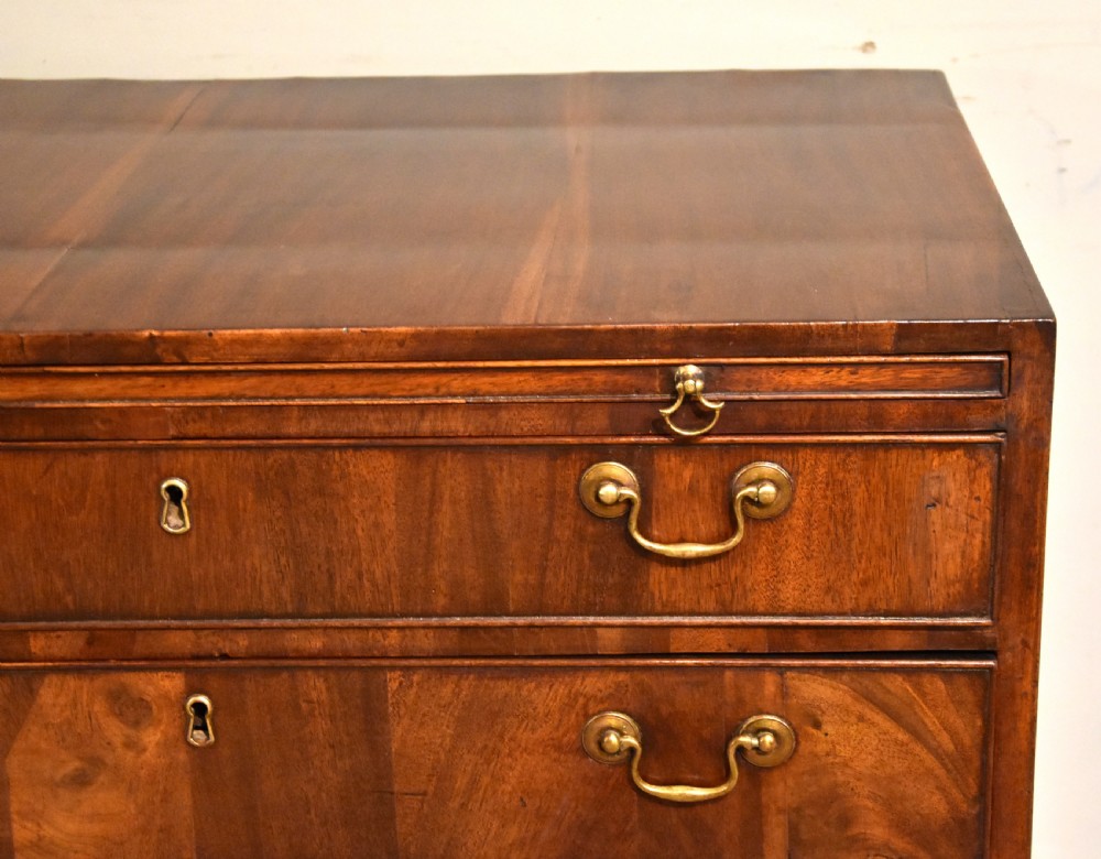 A George III walnut veneered chest of drawers with four graduated drawers, brass handles, and bracket feet. View IX