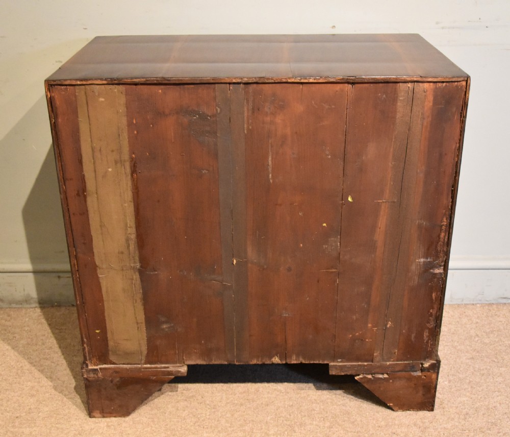 A George III walnut veneered chest of drawers with four graduated drawers, brass handles, and bracket feet. View X