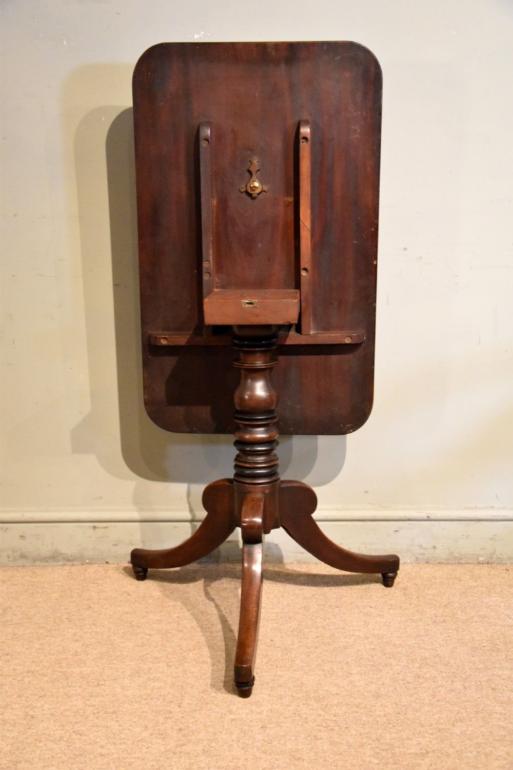 A William IV tilt-top mahogany table with a rich flame veneer rectangular top displayed upright on a turned tripod pedestal base. View III