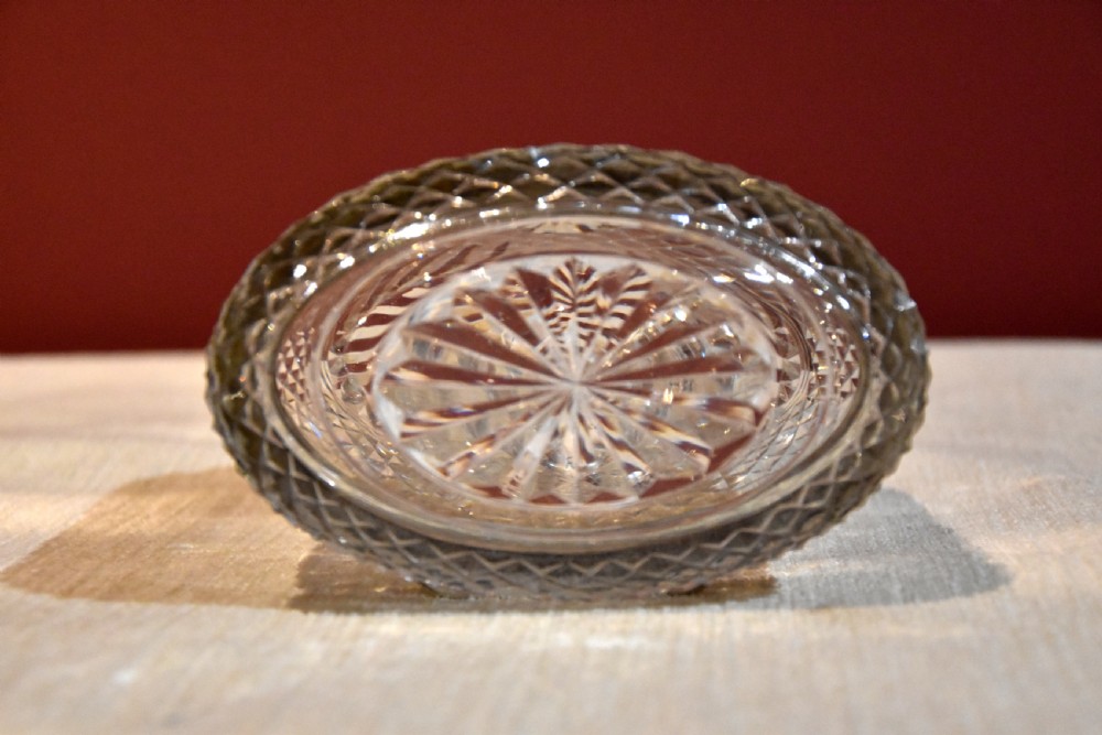 An oval cut glass Georgian tea caddy featuring diamond faceting, a hinged lid, and a silver lock plate with keyhole. View V