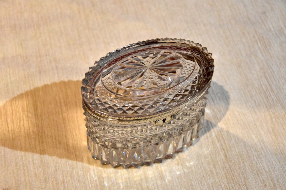 An oval cut glass Georgian tea caddy featuring diamond faceting, a hinged lid, and a silver lock plate with keyhole. View VI