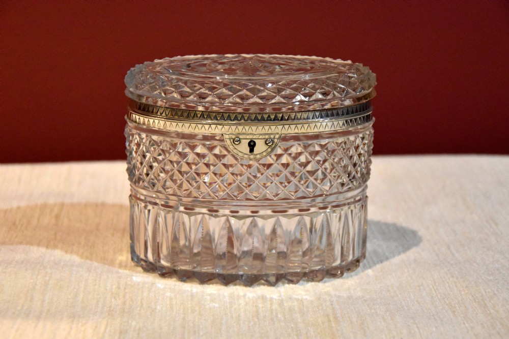 An oval cut glass Georgian tea caddy featuring diamond faceting, a hinged lid, and a silver lock plate with keyhole.