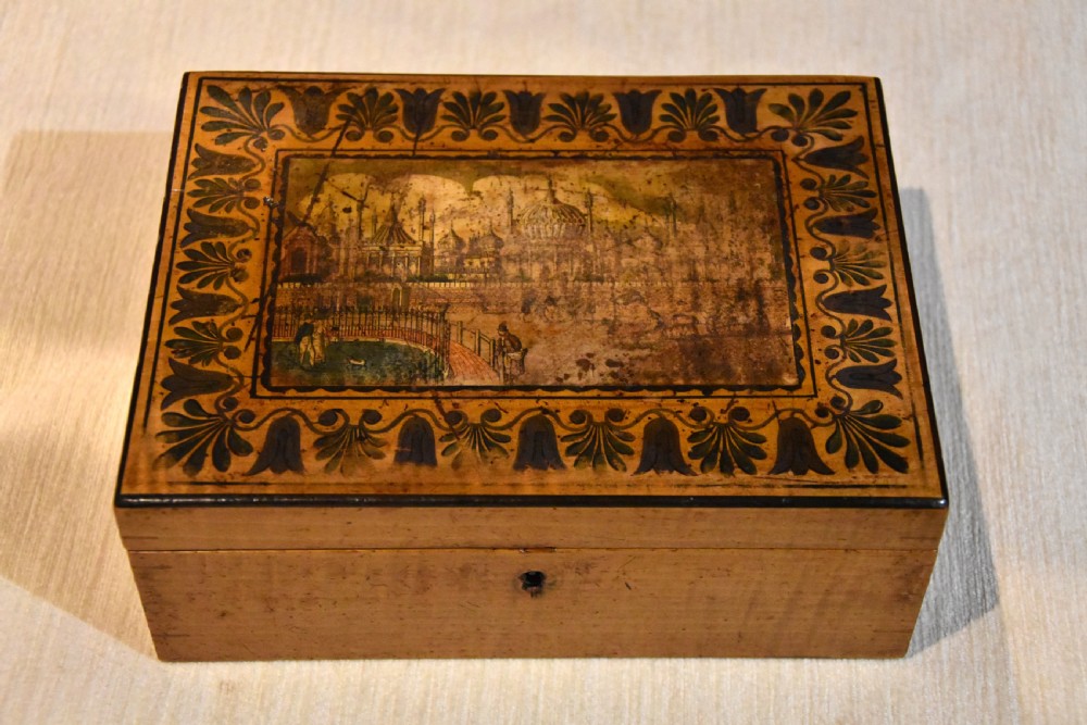 A rectangular 19th-century sycamore wood box featuring a printed architectural scene on the lid surrounded by a stylized leaf border and a keyhole on the front.