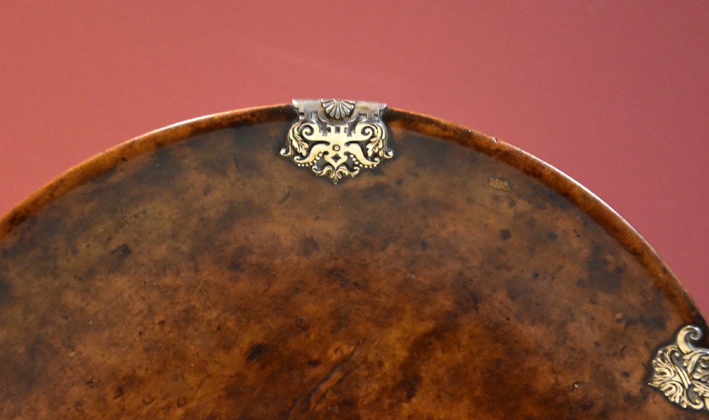 A circular shallow bowl carved from figured brown burr wood, featuring six chased silver mounts positioned around the rim. View II