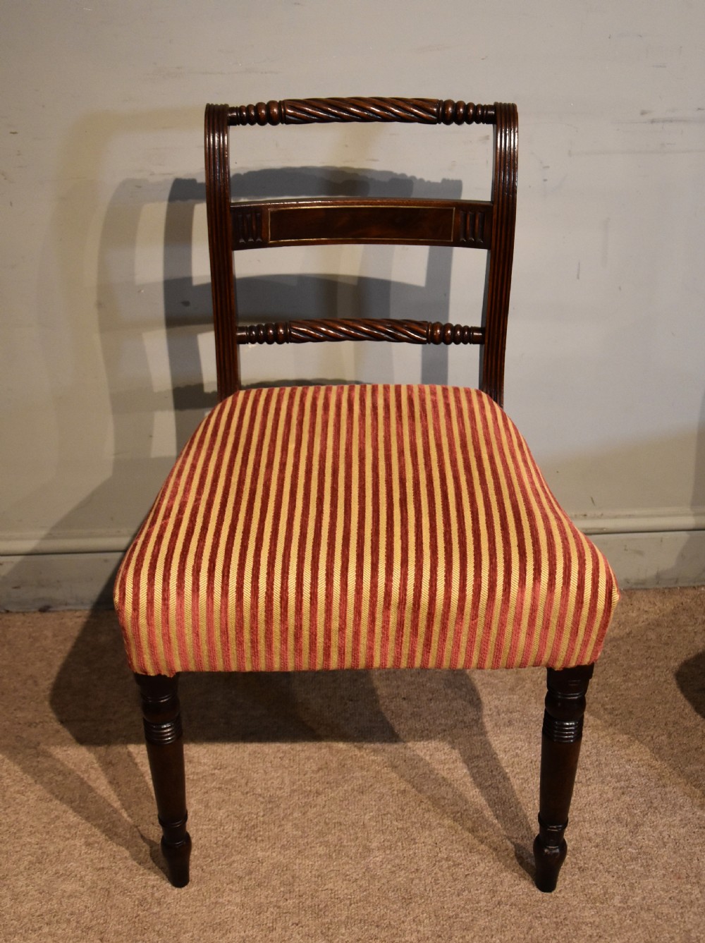 A set of eight Regency mahogany dining chairs featuring carved rope-twist top rails and striped upholstered seats. View IV