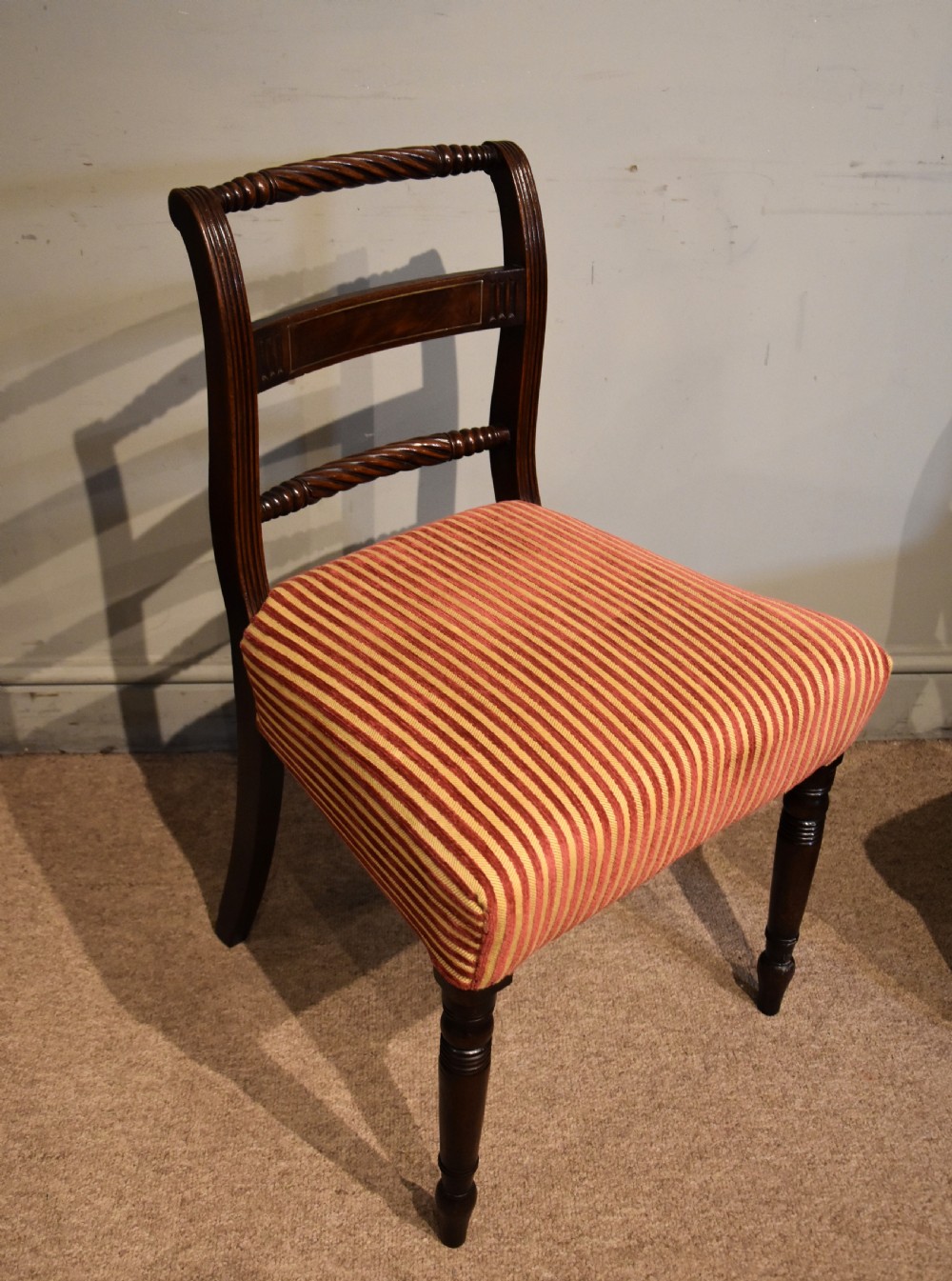 A set of eight Regency mahogany dining chairs featuring carved rope-twist top rails and striped upholstered seats. View V