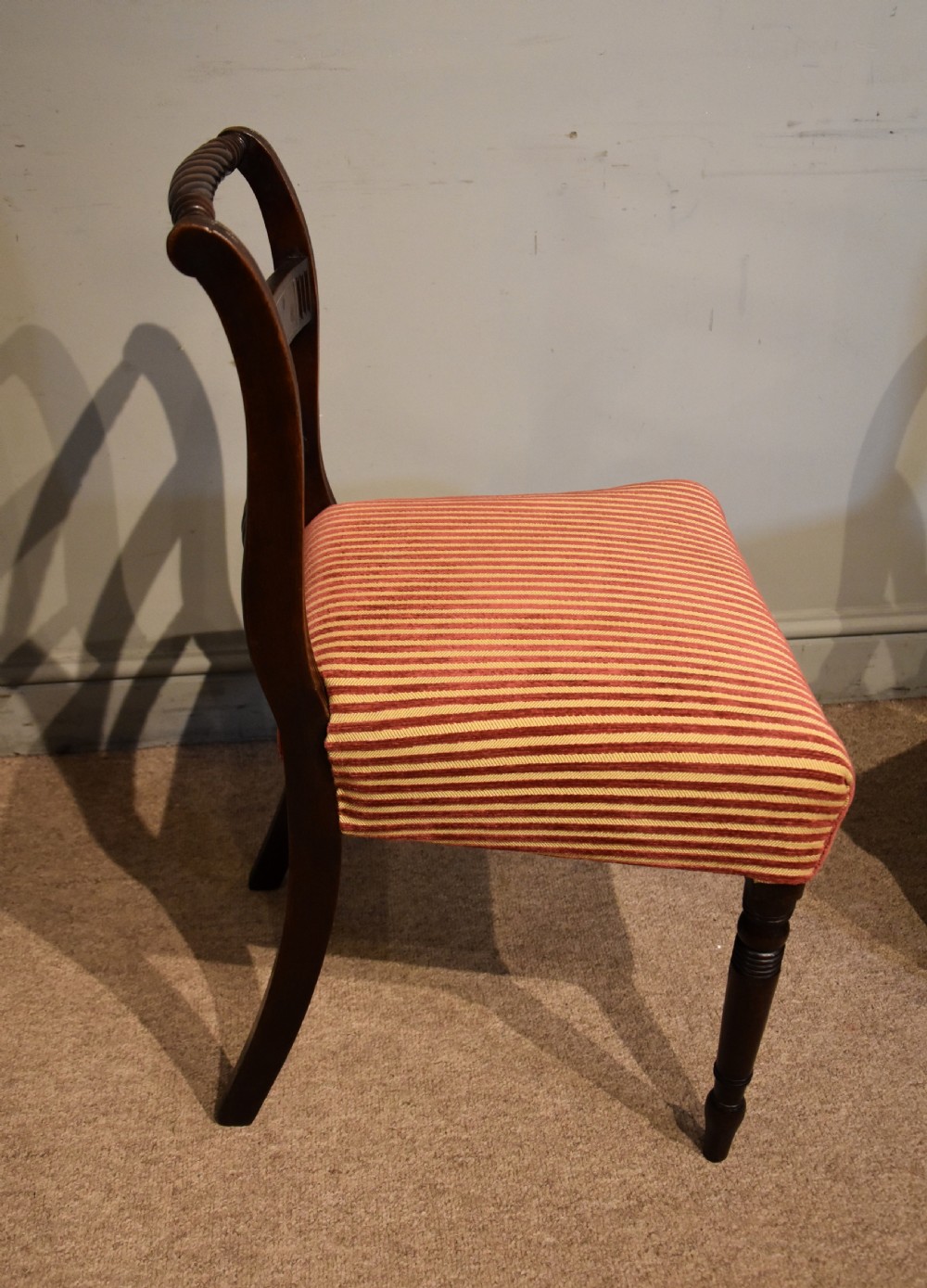 A set of eight Regency mahogany dining chairs featuring carved rope-twist top rails and striped upholstered seats. View VI
