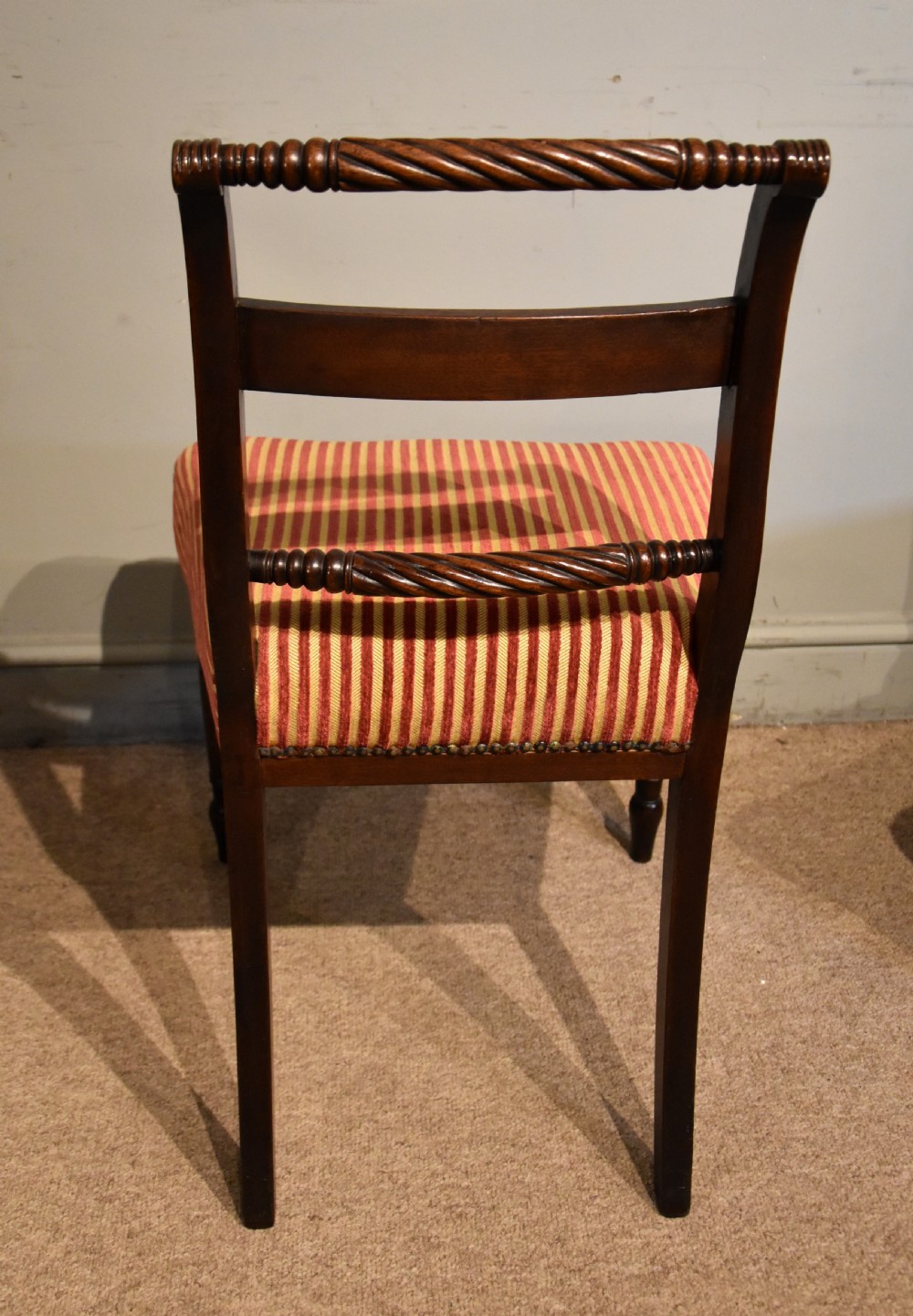 A set of eight Regency mahogany dining chairs featuring carved rope-twist top rails and striped upholstered seats. View VII