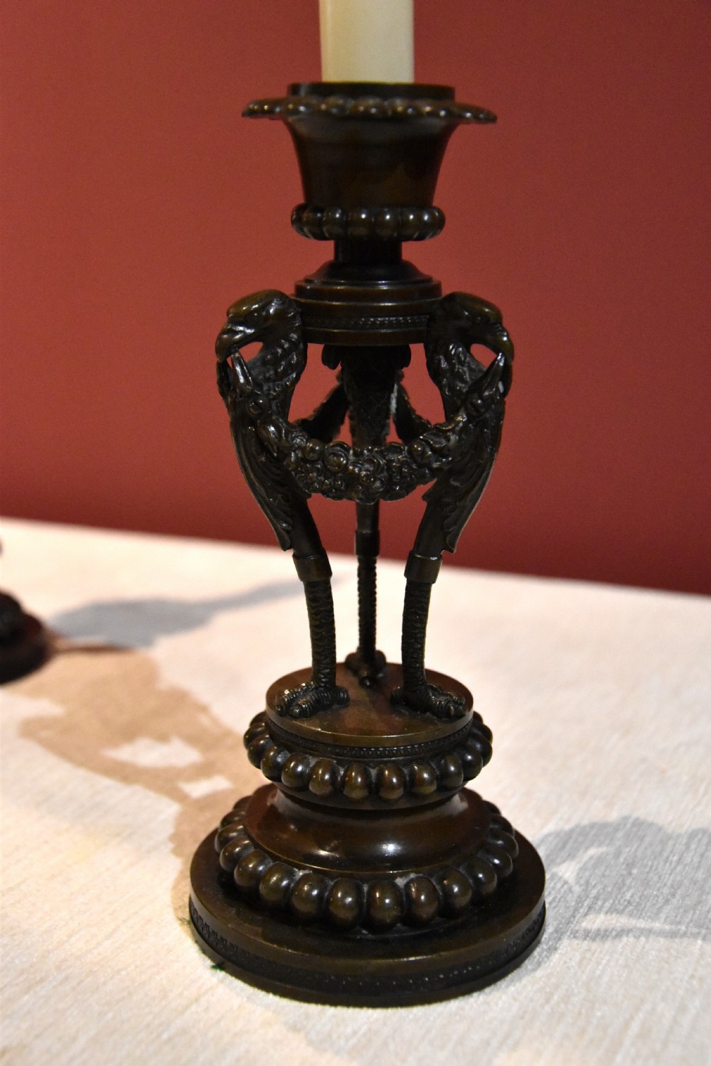 A pair of dark patinated bronze Regency candlesticks featuring detailed bird leg supports, draped floral garlands, and beaded circular bases. View IV