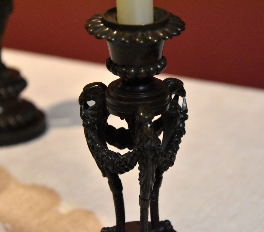 A pair of dark patinated bronze Regency candlesticks featuring detailed bird leg supports, draped floral garlands, and beaded circular bases. View V