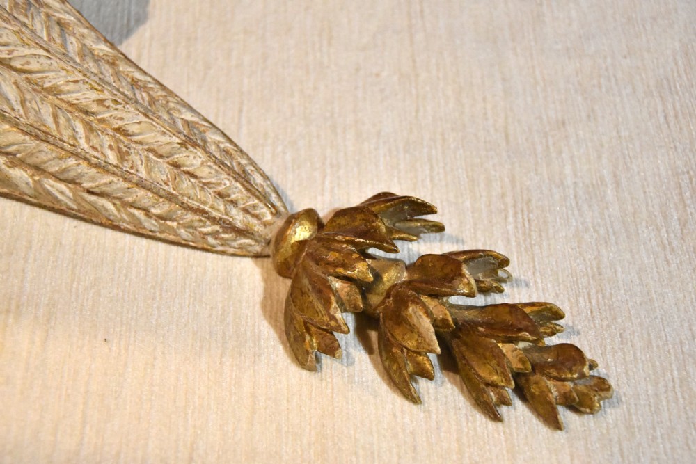 An 18th-century carved wall bracket featuring a semicircular gilded top shelf with beaded molding above a tapered white body with leaf carving and a drop leaf finial. View V