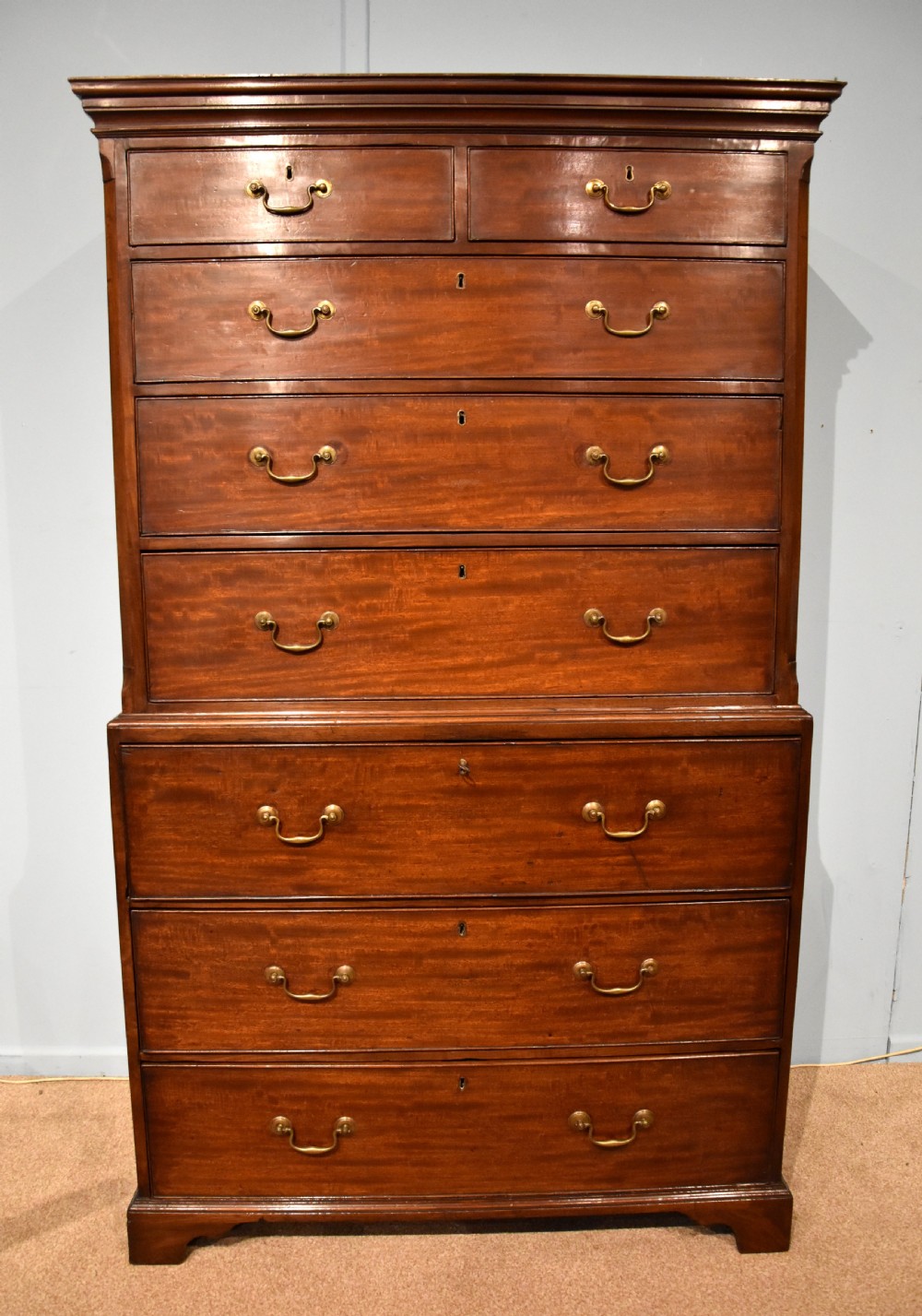An eighteenth-century mahogany chest on chest featuring two short over six long graduated drawers with brass swan-neck handles and bracket feet.