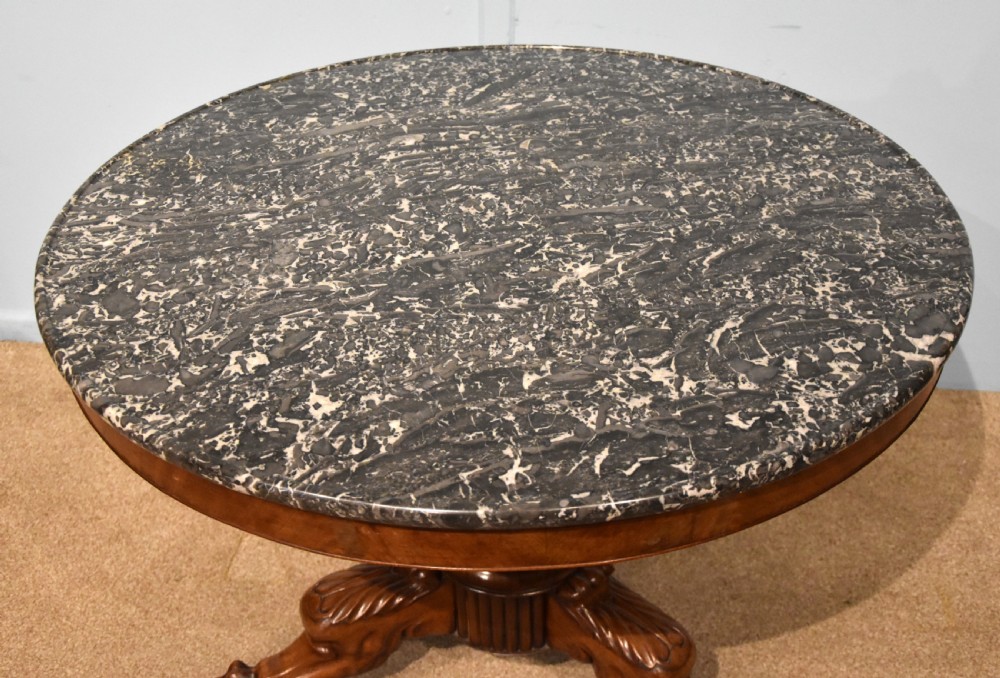 A 19th-century French mahogany gueridon table featuring a circular dark marble top supported by a reeded pedestal stem and carved triform base with paw feet. View V