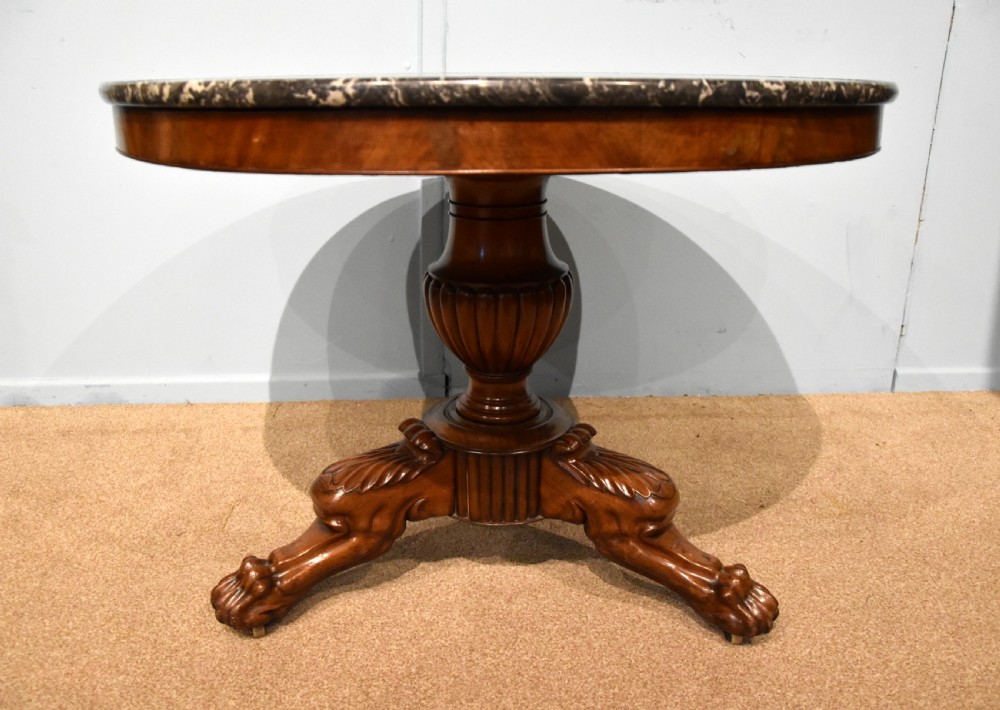 A 19th-century French mahogany gueridon table featuring a circular dark marble top supported by a reeded pedestal stem and carved triform base with paw feet. View VI