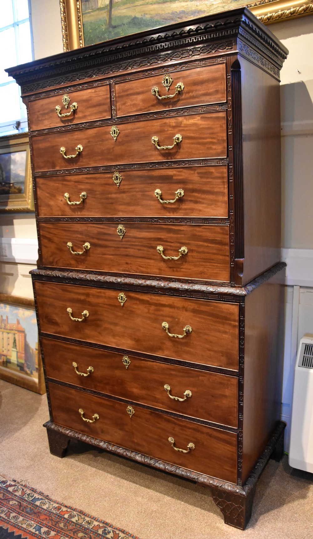 An eighteenth-century carved mahogany chest on chest featuring geometric fretwork mouldings, brass swan-neck handles, and carved bracket feet. View VI