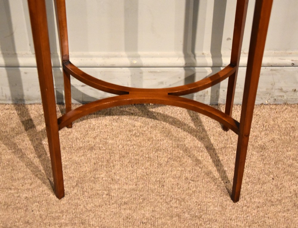 An oval Sheraton Revival occasional table crafted from satinwood with crossbanded border inlay, slender tapered legs, and a curved X-frame stretcher. View IV