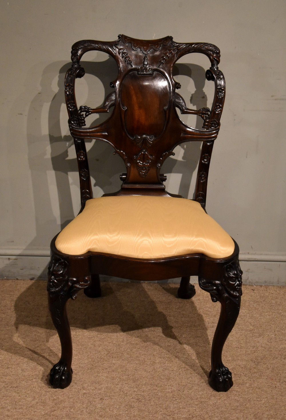 A 19th-century Cuban mahogany side chair featuring an openwork carved back, gold fabric seat, and cabriole legs with claw and ball feet.
