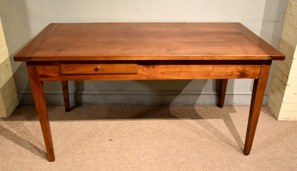 A mid 19th-century French farmhouse table in warm brown fruitwood featuring a single frieze drawer and tapered square legs.