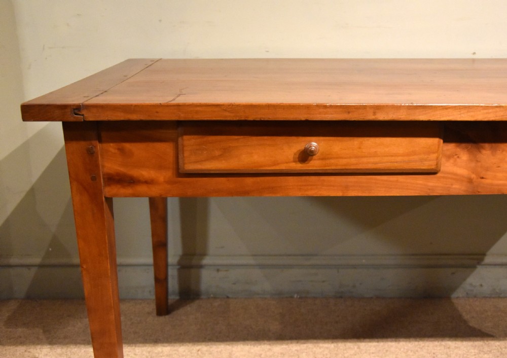A mid 19th-century French farmhouse table in warm brown fruitwood featuring a single frieze drawer and tapered square legs. View V