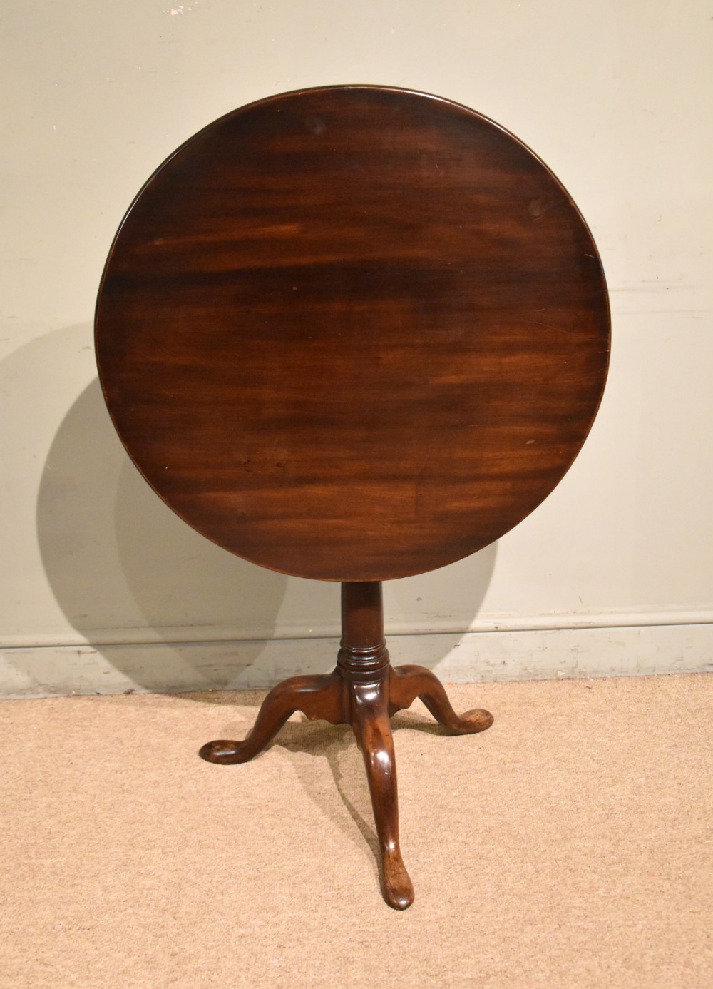 A mid-18th-century Georgian mahogany tripod table featuring a circular tilt top supported by a central turned column and three cabriole legs.