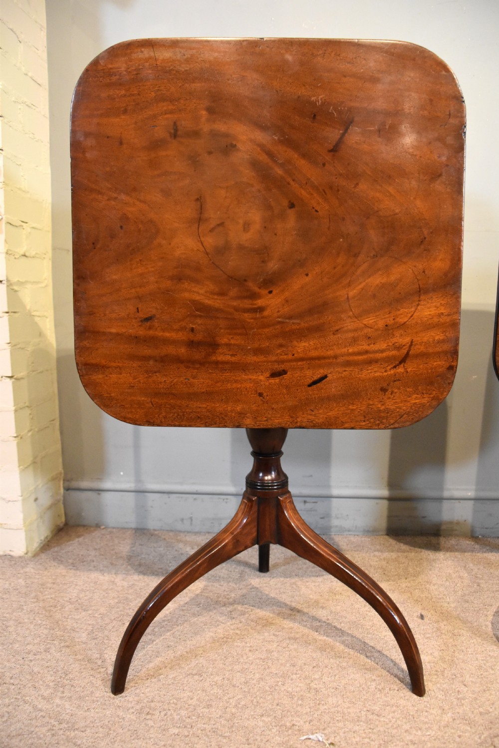 A matched pair of mahogany tripod tables featuring turned pedestals and square tops with rounded corners. View VI