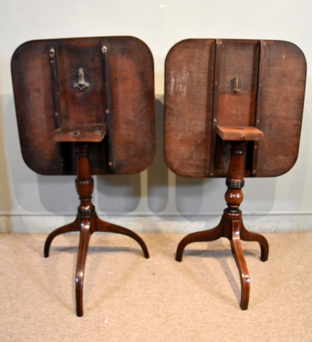 A matched pair of mahogany tripod tables featuring turned pedestals and square tops with rounded corners. View VII