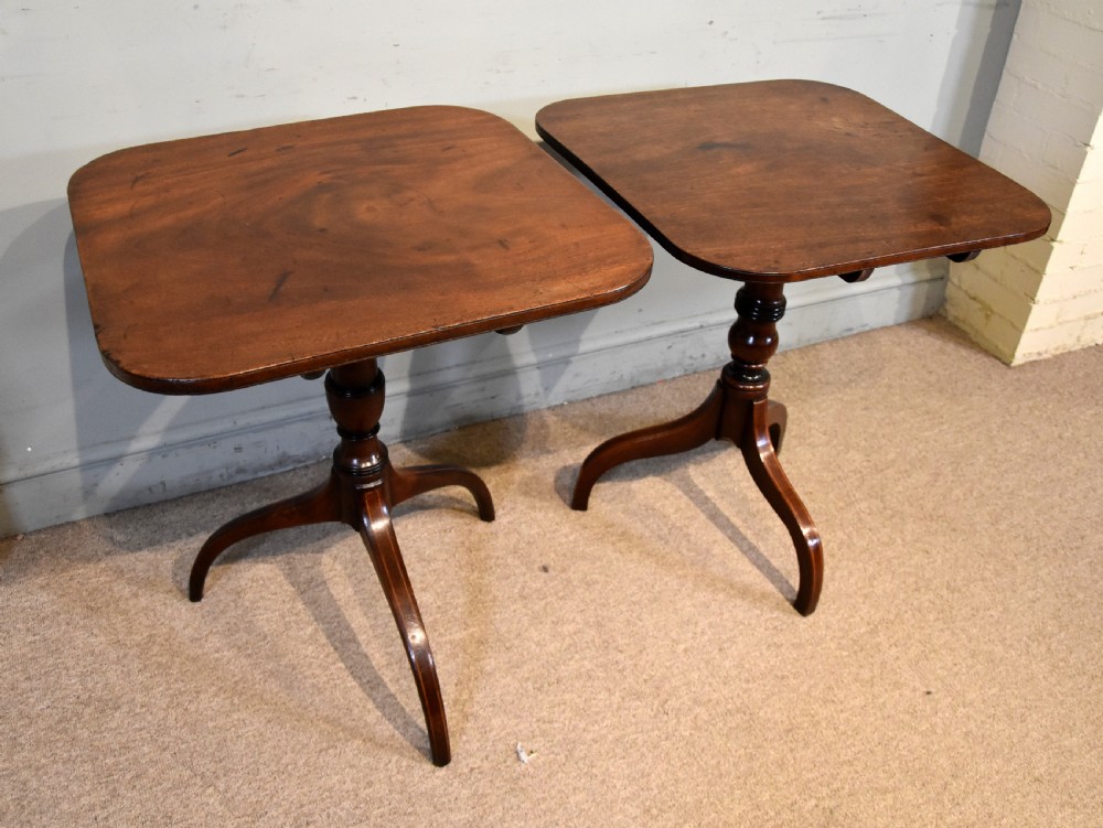 A matched pair of mahogany tripod tables featuring turned pedestals and square tops with rounded corners. View IX