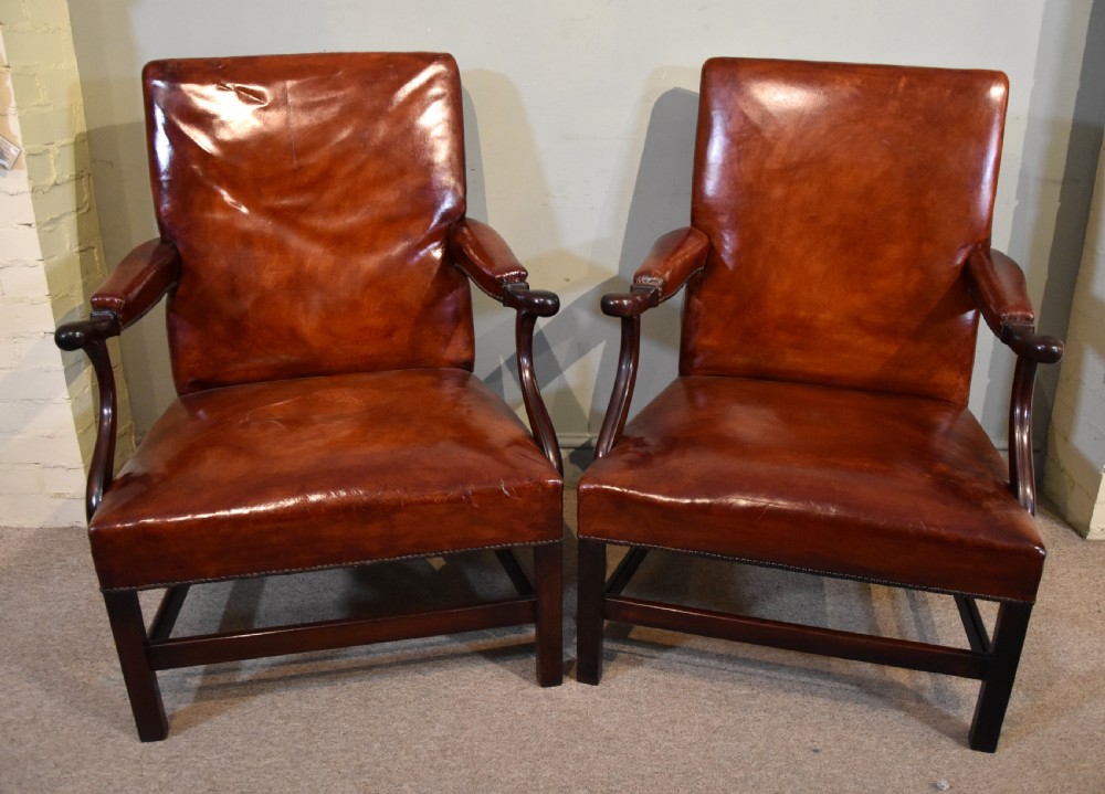 A pair of George III style mahogany armchairs with warm brown leather upholstery, padded open arms, and brass stud trim. View III