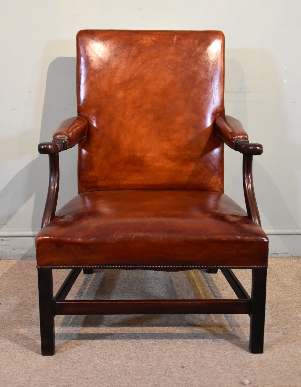 A pair of George III style mahogany armchairs with warm brown leather upholstery, padded open arms, and brass stud trim. View IV