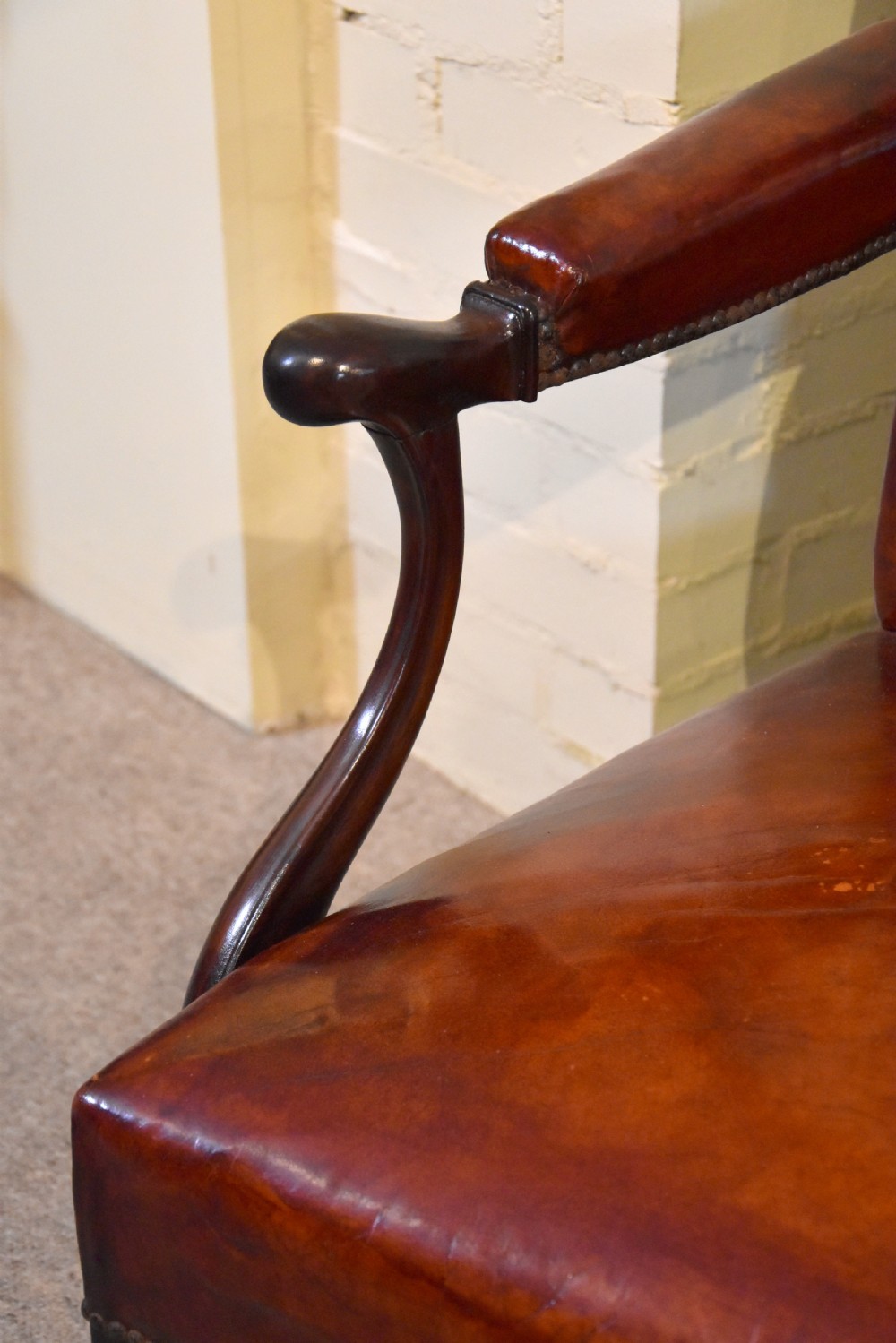 A pair of George III style mahogany armchairs with warm brown leather upholstery, padded open arms, and brass stud trim. View VI