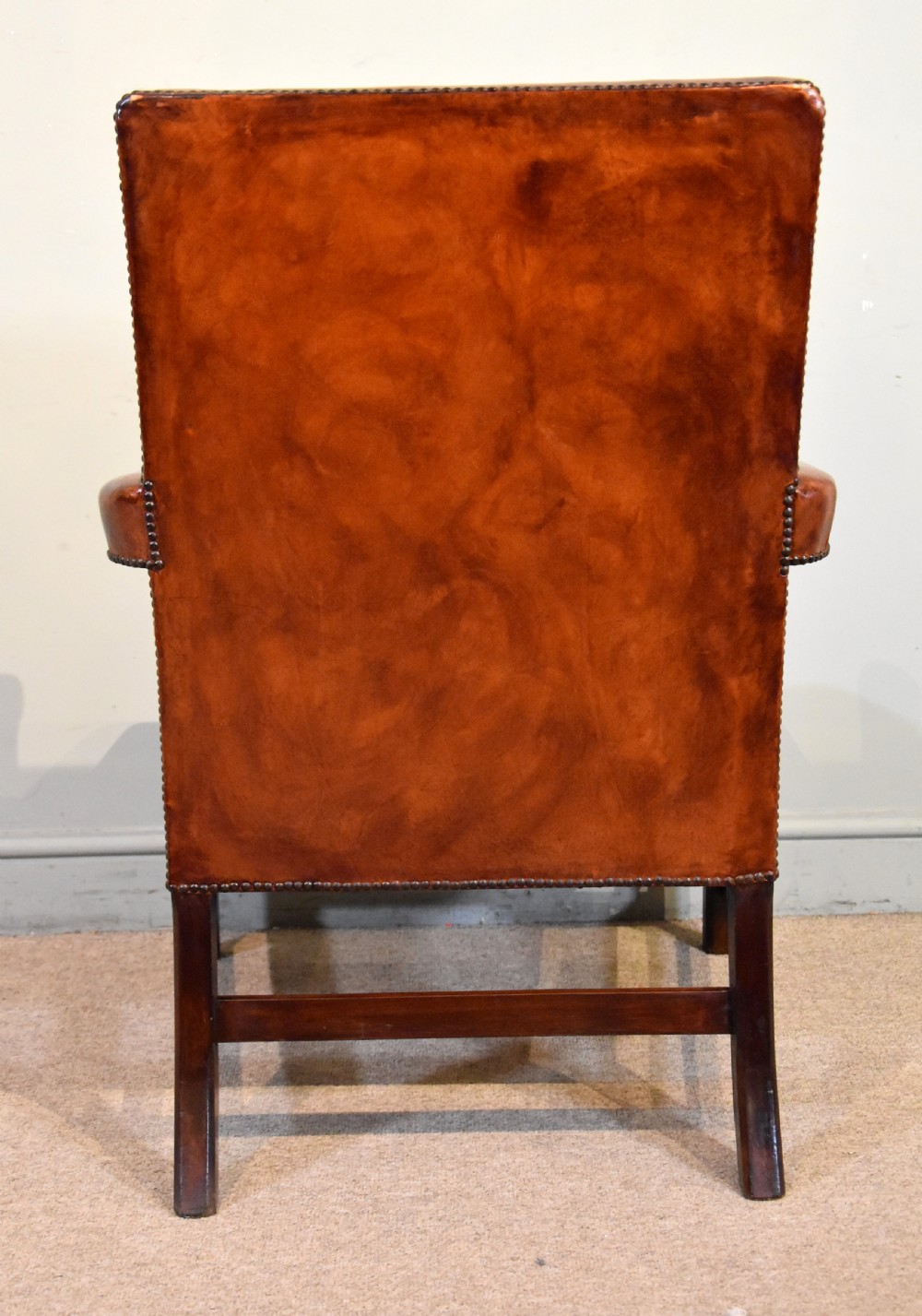 A pair of George III style mahogany armchairs with warm brown leather upholstery, padded open arms, and brass stud trim. View VII